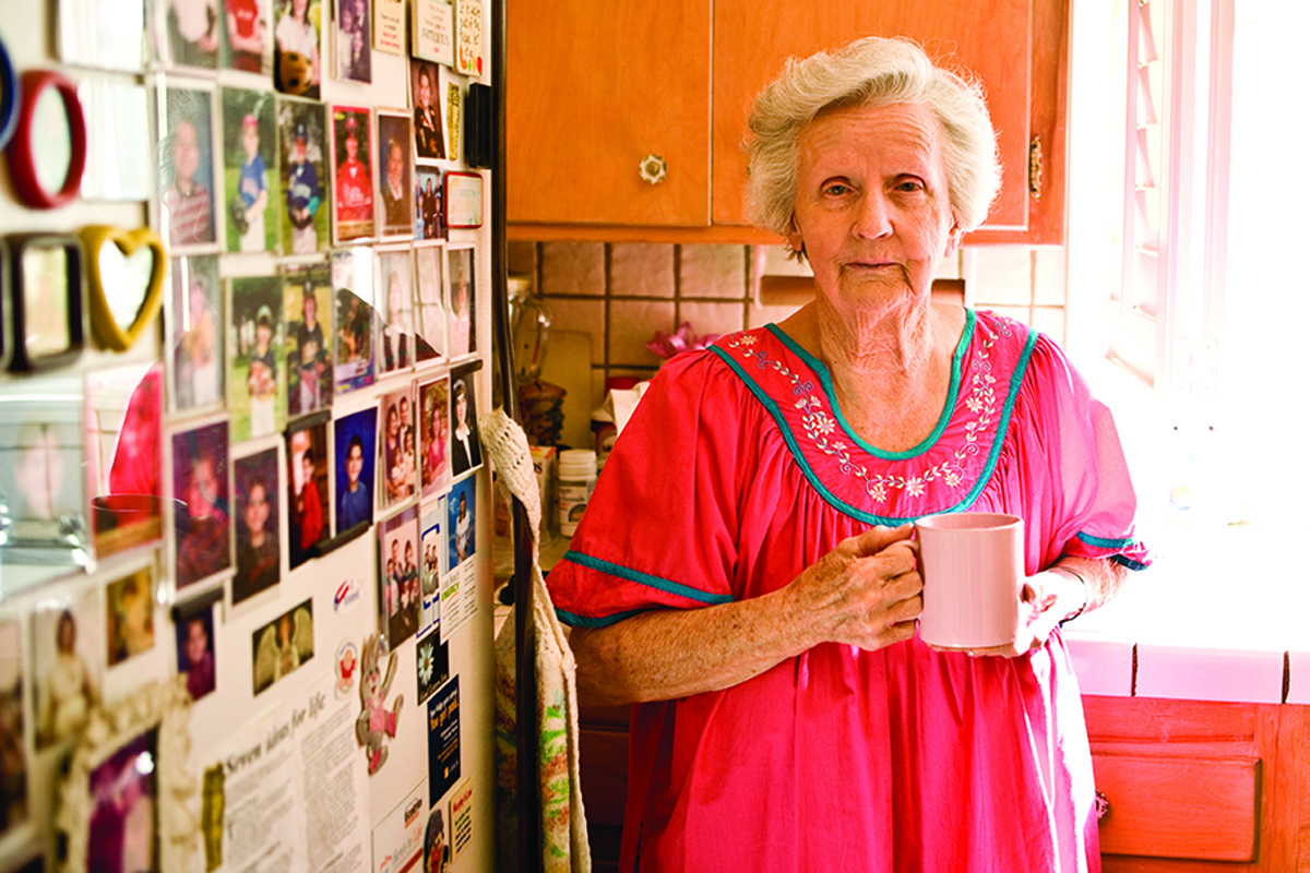Elderly woman in her kitchen holding a cup of coffee