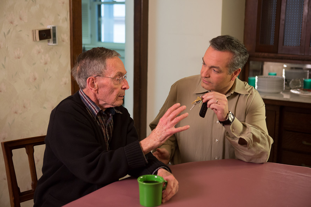 Adult son taking keys from aging man