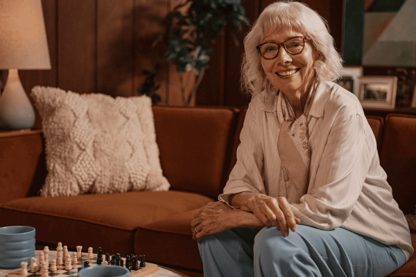 Older adult woman smiling as she plays chess to keep her mind active and engaged