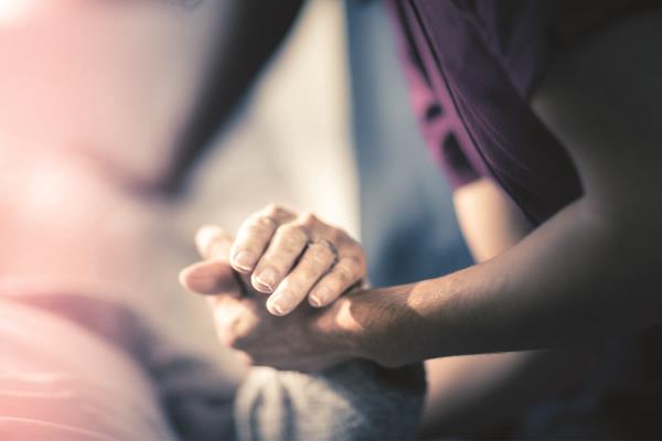 Caregiver and Senior Holding Hands