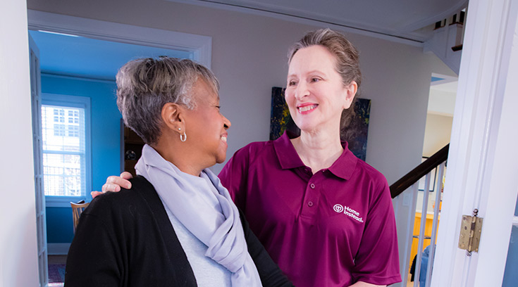 Caregiver and senior walking inside home