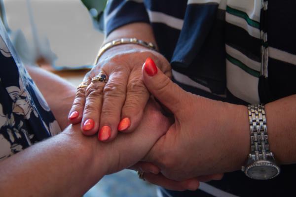 Two people gently holding the hands